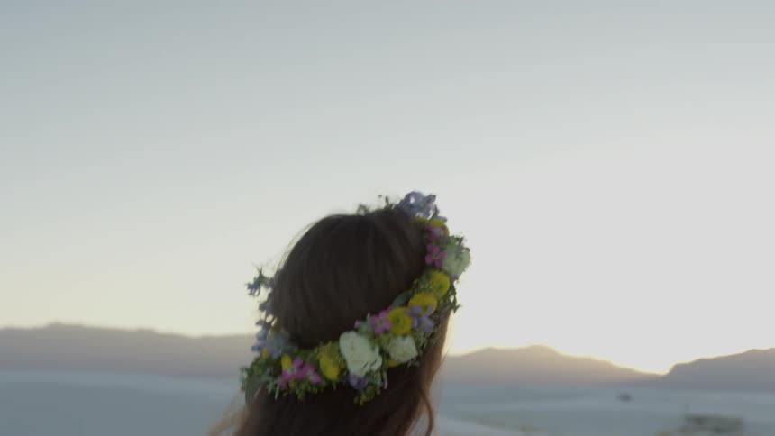 A woman walking in a sandy locale turns to smile