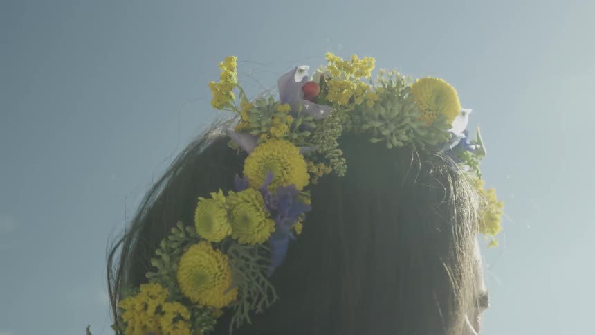 A woman is wearing a wreath of flowers on her head