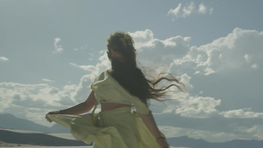 A woman twirls around in a yellow dress