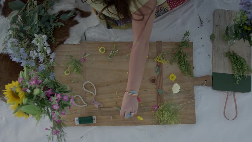 Woman arranging cut flowers on wooden board