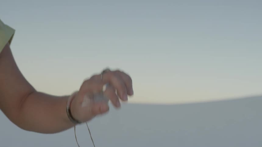 A woman picks up sand and lets it fall from her hand