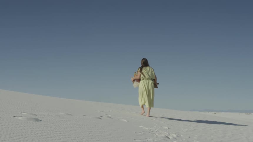 A woman walks alone in a desert
