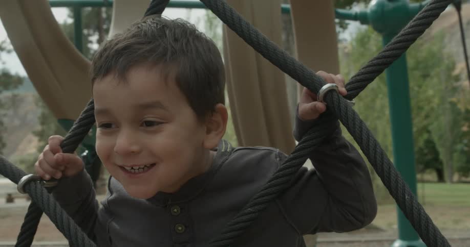 A boy plays on a rope net on a playground
