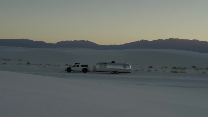 A silver bullet trailer is parked in the desert