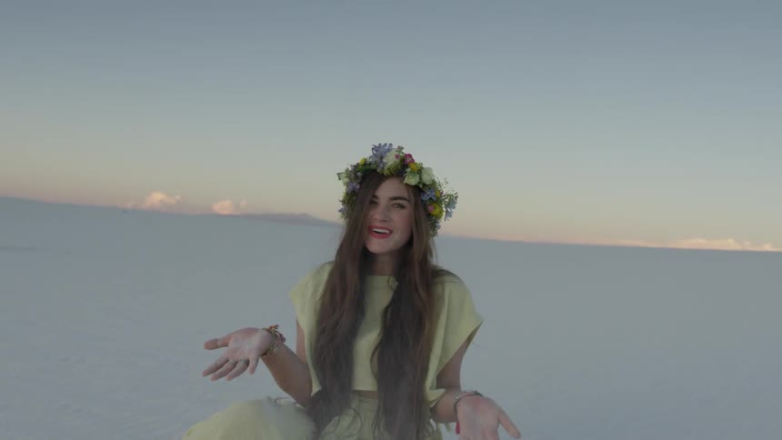 A woman with flowers in her hair throws sand up in the air