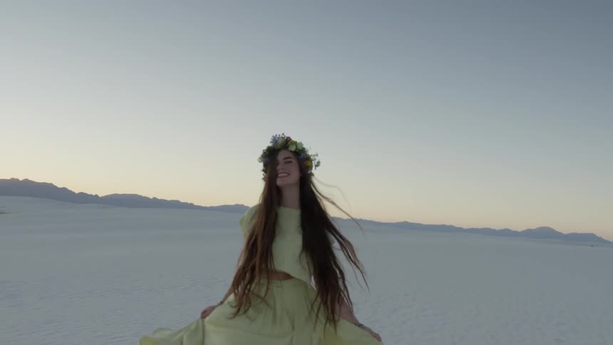 A woman laughs and skips as she walks over white sand