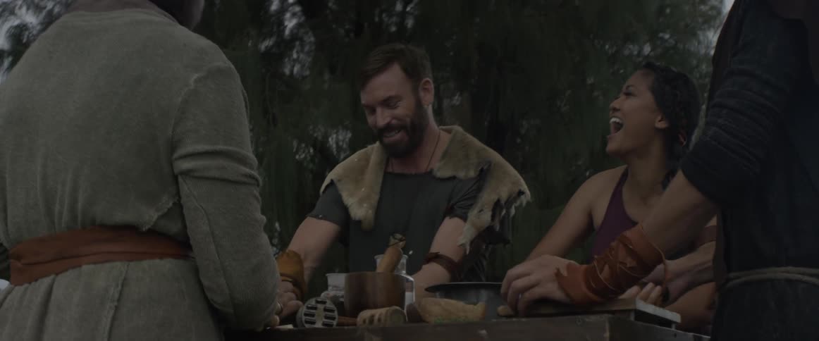 Friends smile and laugh while preparing food outside