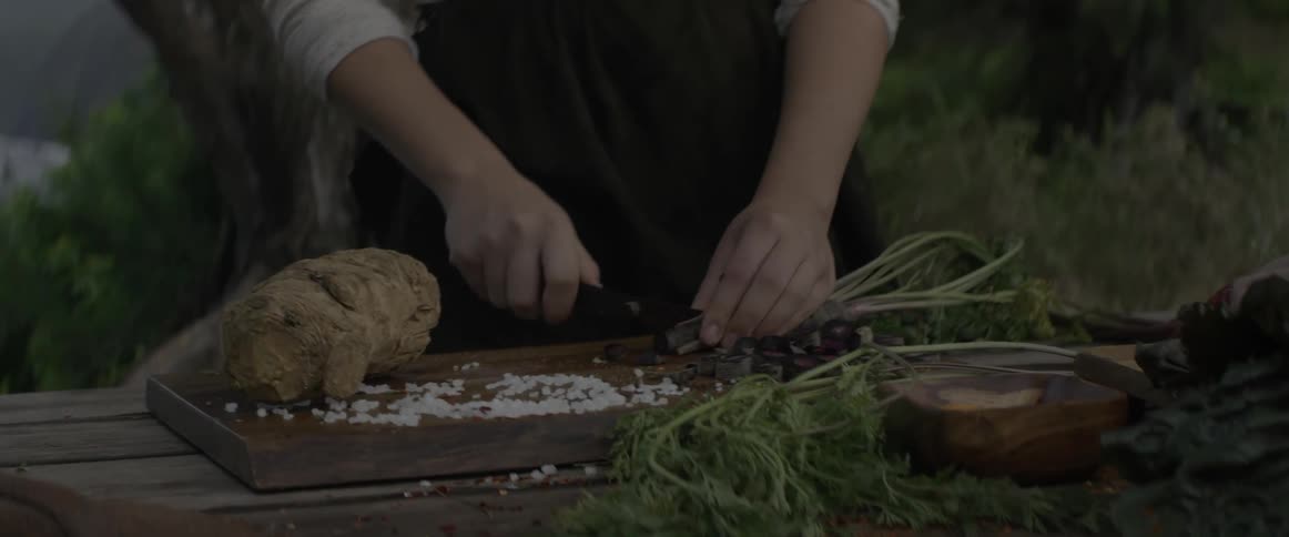 A girl cuts vegetables outside on a cutting board