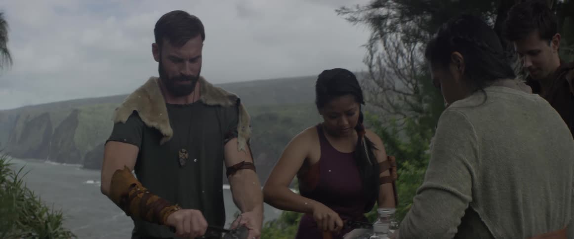 Friends prepare food with knives outside on an overcast day