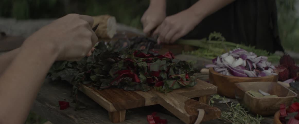 People are cutting vegetables on a board