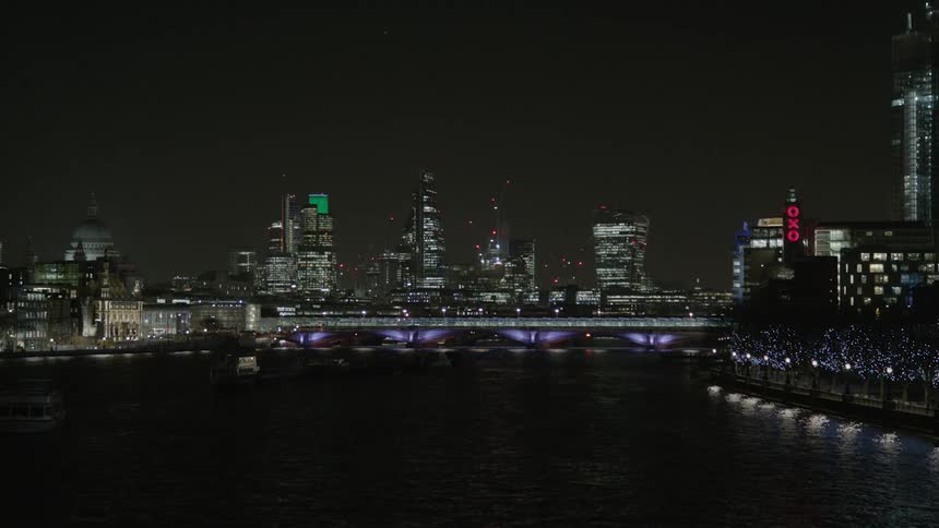A city skyline is being filmed at night from the water