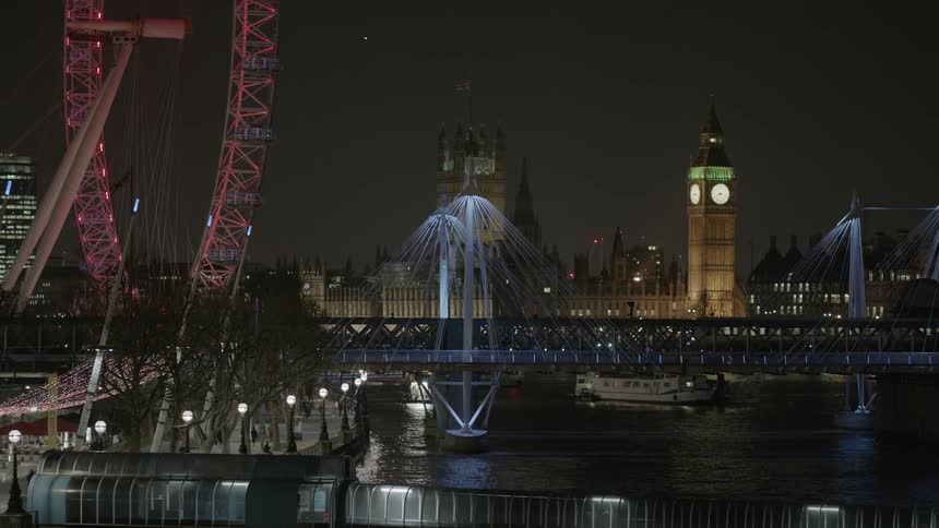 A train crosses a lit bridge on the thames in london