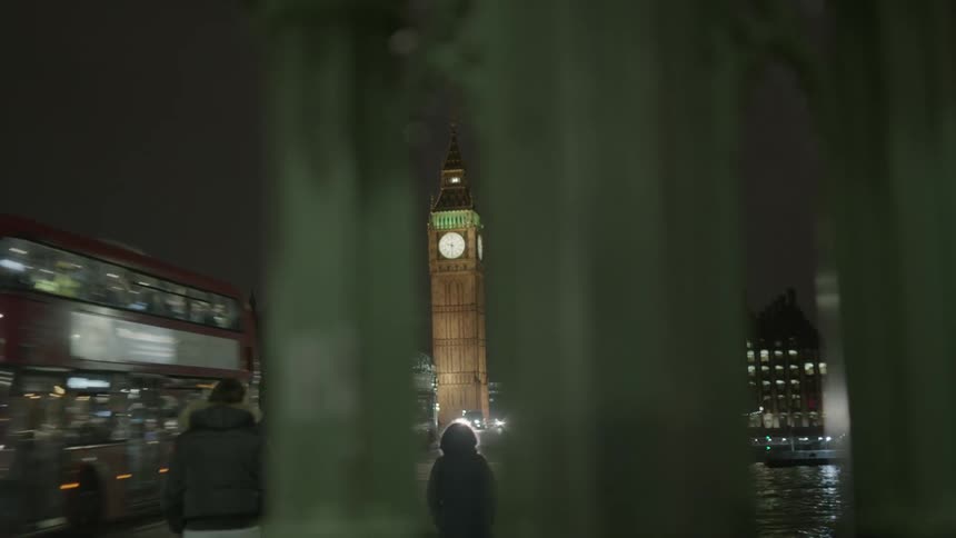 Pedestrians and cars travel on a city street at night