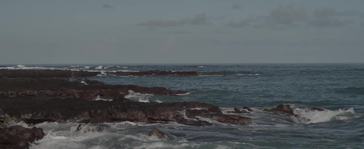 Waves are crashing along the shore line of a beach