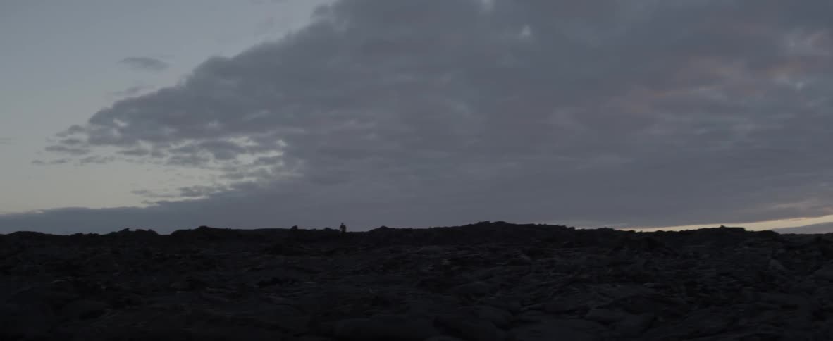 Someone in the distance is standing on top of some rocks with the sky in the background