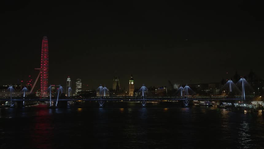 The city ahead is dark at night with a tall building with red lights