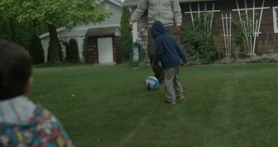 A family is playing soccer on the lawn