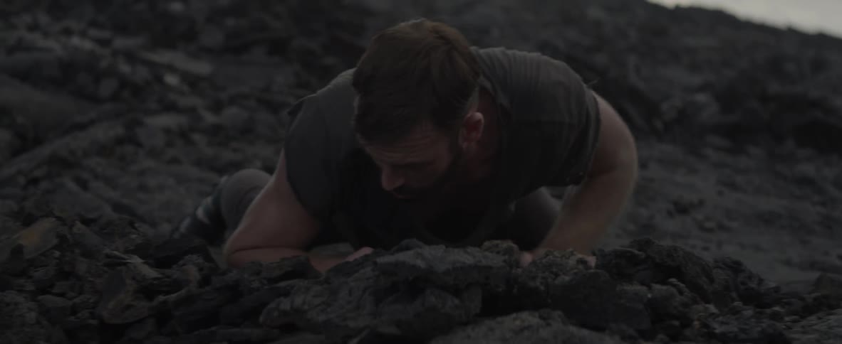 Man climbing up off rocks looking around