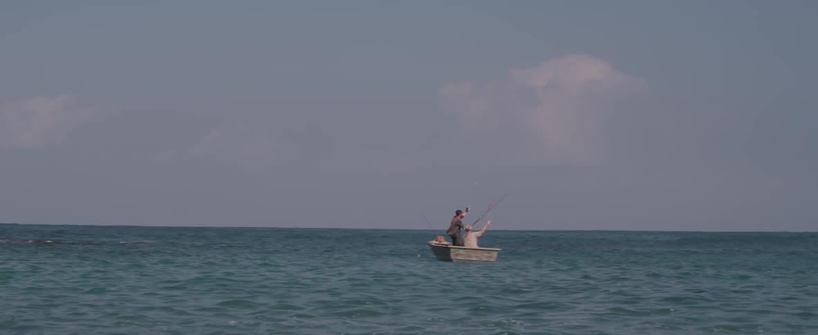 Two people fish from a rowboat in the ocean