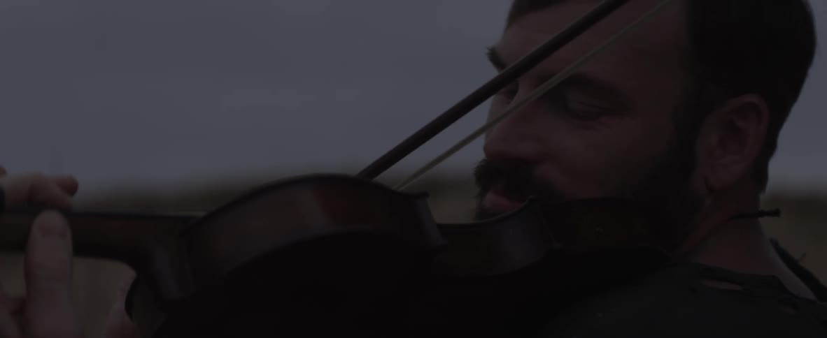 A man is smiling as he plays the violin