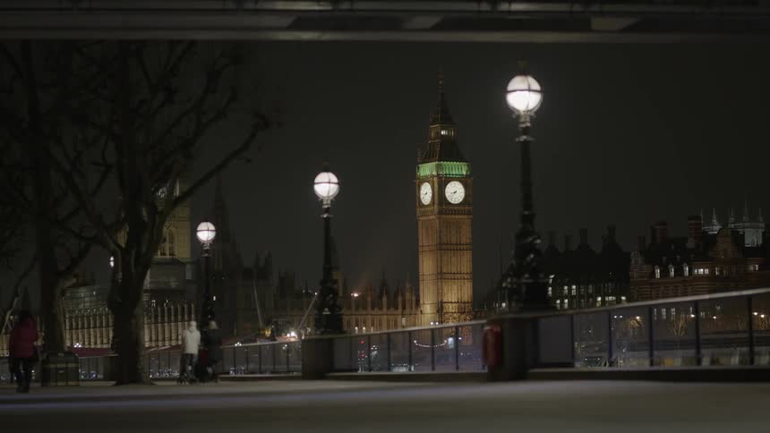 People walking over a bridge in a city at night