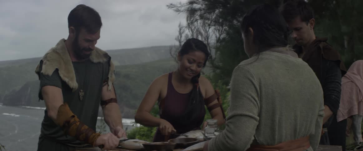 People cut scales off of fish outside on the coast