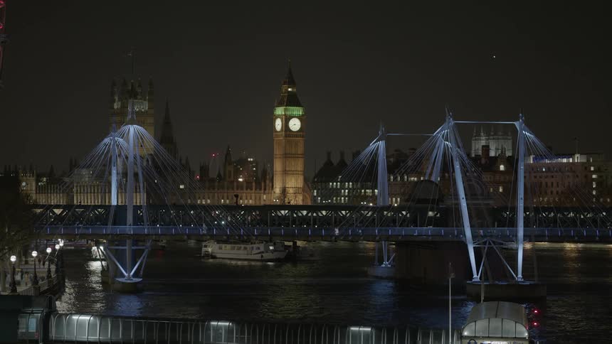 Monorail travels over a bridge in a lit up city at night
