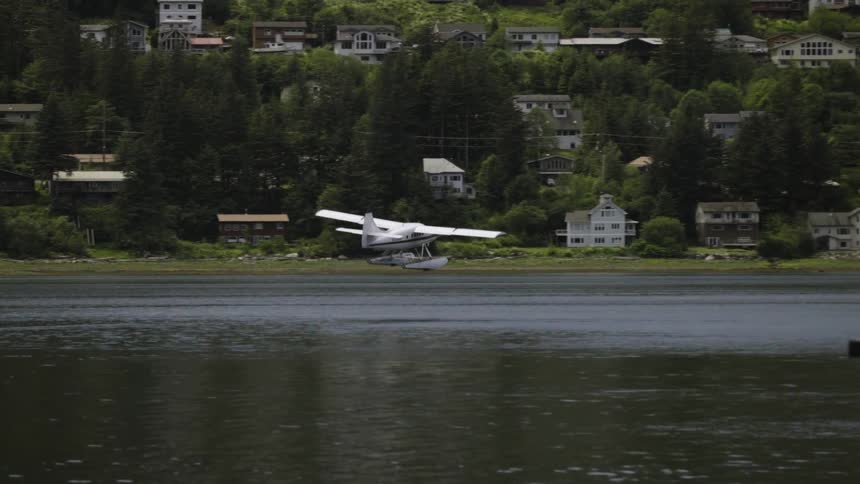 A small aircraft flies just above the surface of a lake