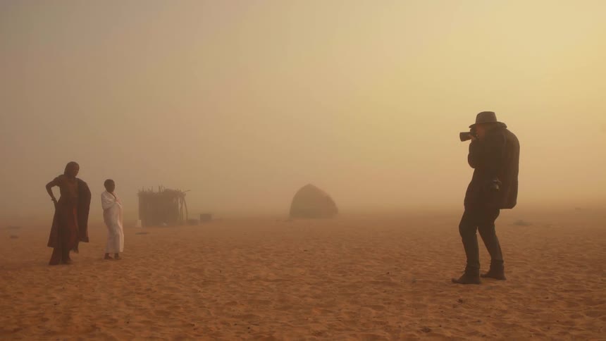 A man is photographing people walking in the sand