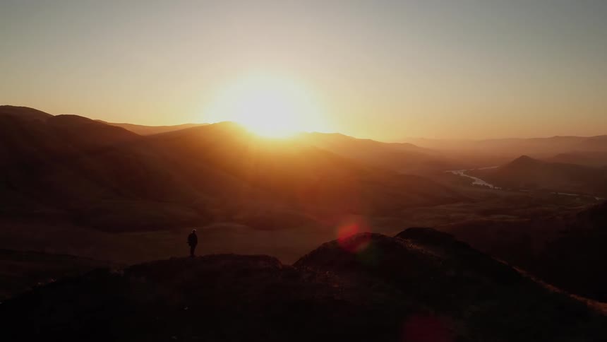 Person standing on a hill watching the sunset