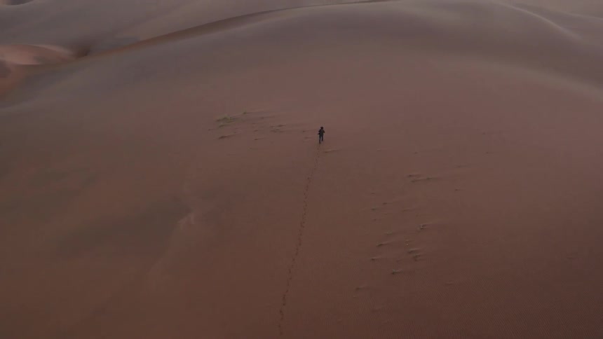 A single person is walking across the desert below