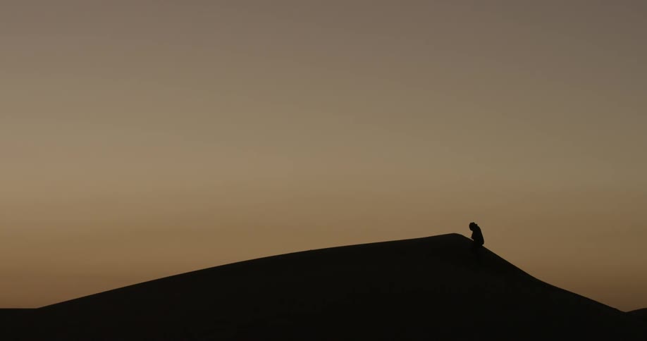 A person hikes up a tall sand dune