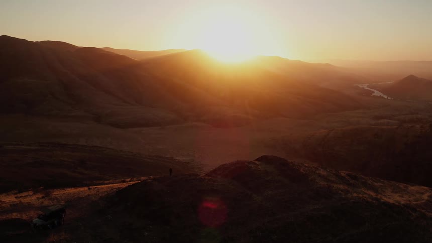 The sun is rising above the hills of a desert valley