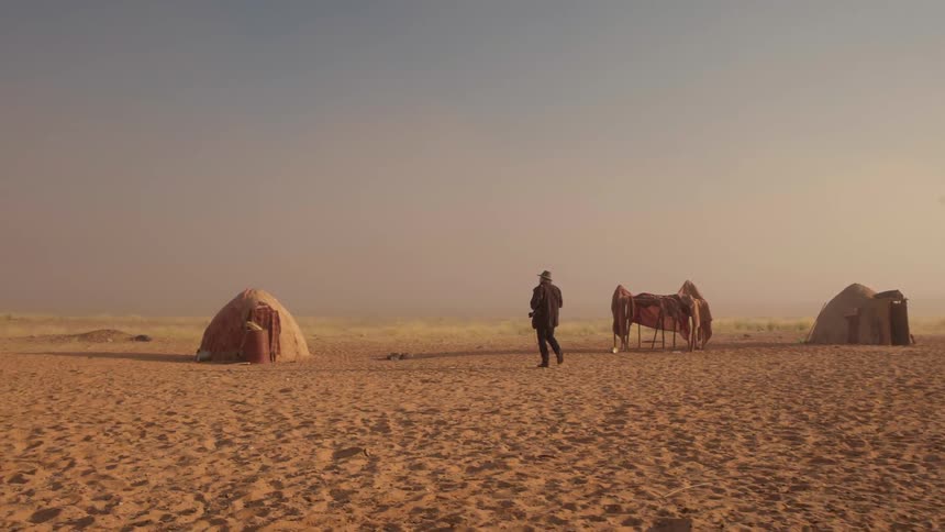 A person walks over to a hut and takes a photograph