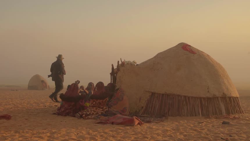 A man is taking pictures of the tents and people in the desert