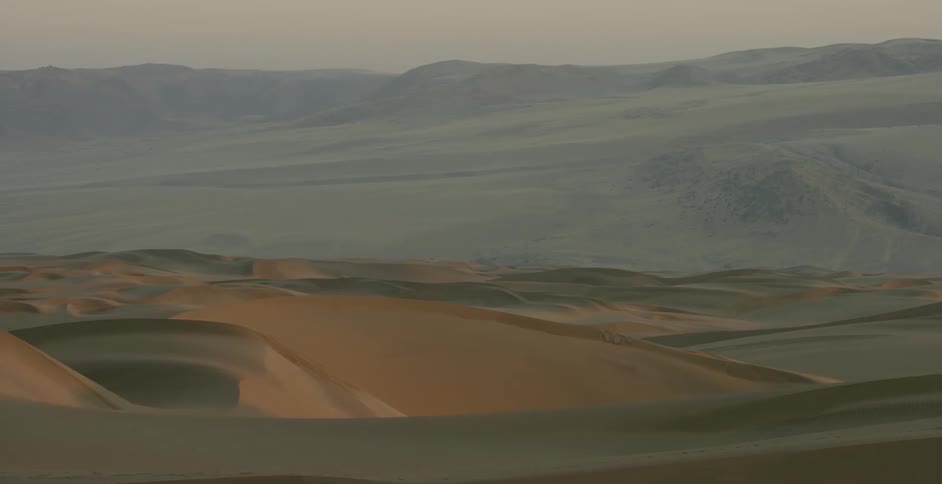 The sand dunes lead to mountains ahead