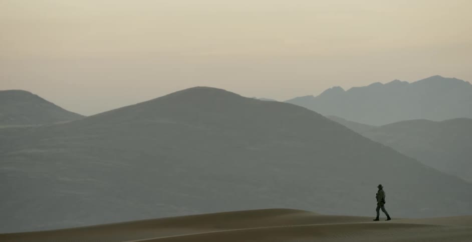 A man walks along a sandy ridge