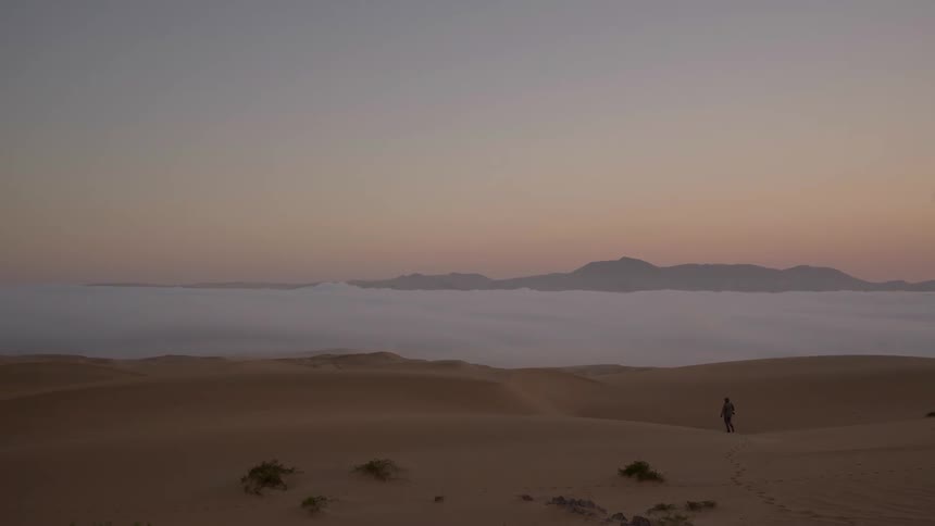 A man is walking alone in the desert