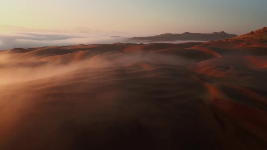 Clouds hover over sand dunes at sunset
