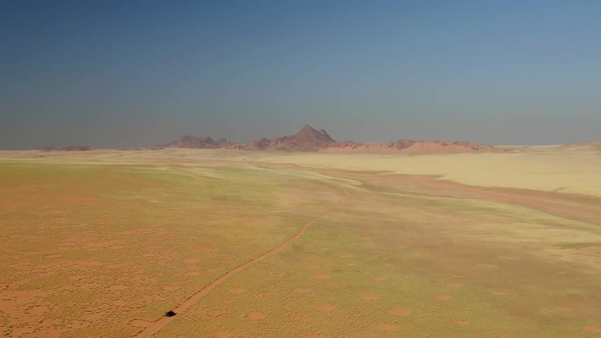 A truck travels on a dirt road in the desert