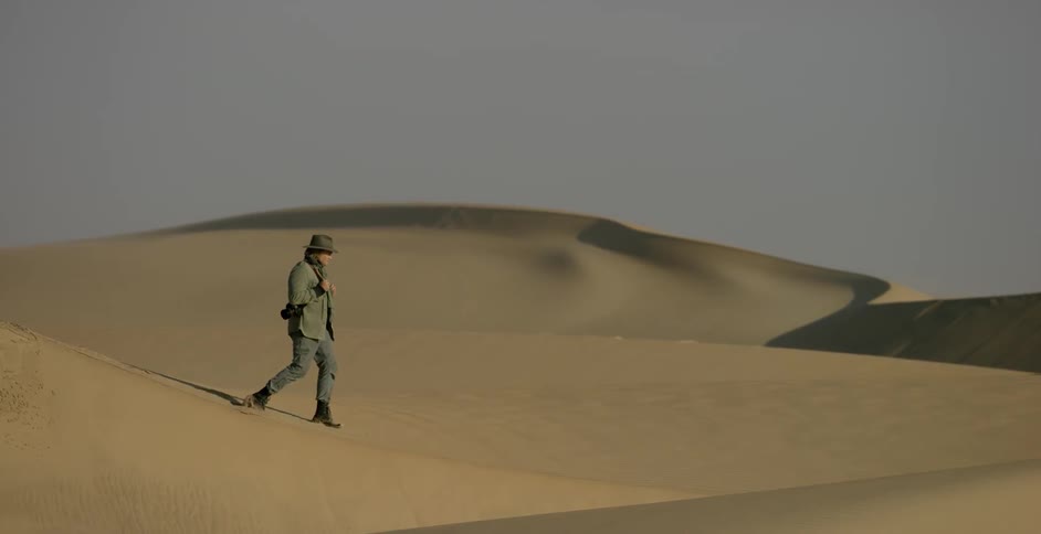 A man is climbing down a large sand dune