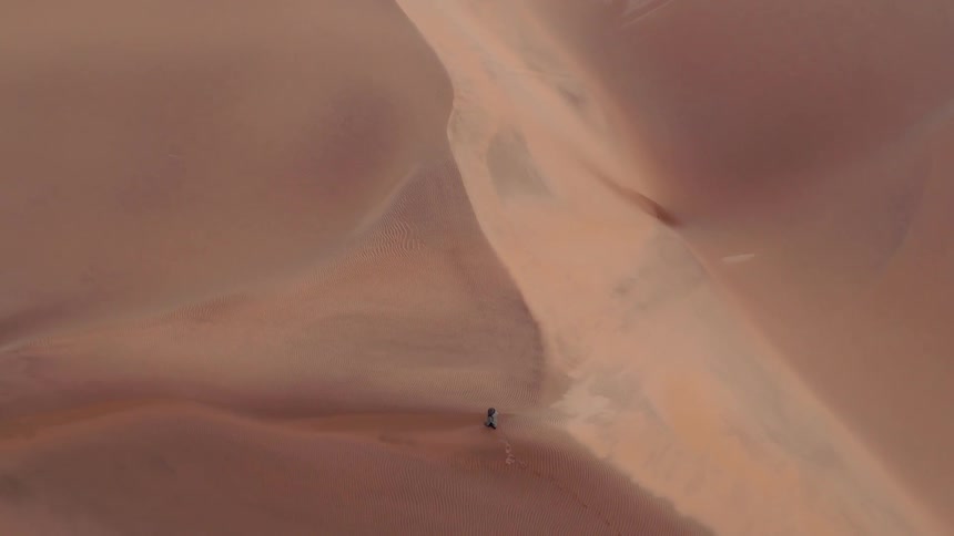 Person walks through sand dunes in the desert