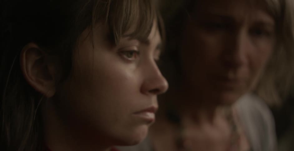 A woman looks sad as another watches on