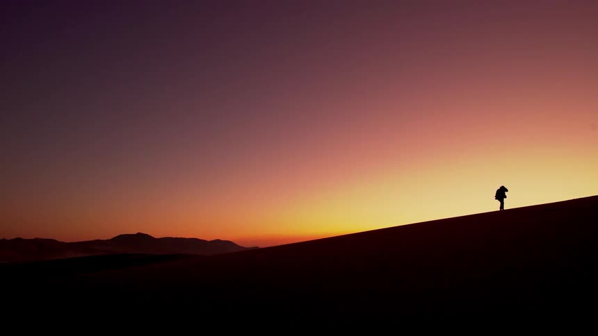 A person walks up the hill at dawn