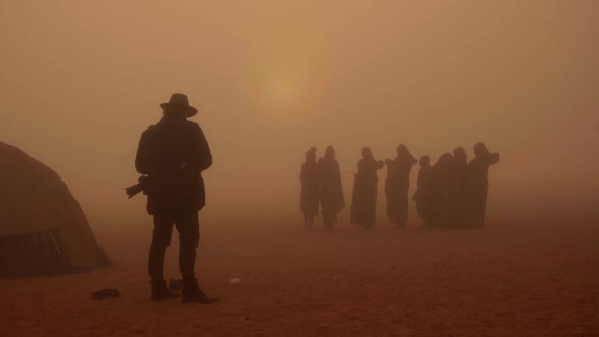 Man records group of people in a dusty desert