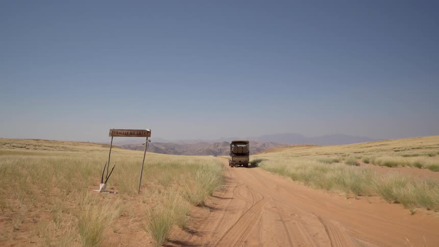 A truck is traveling down a dirt desert road