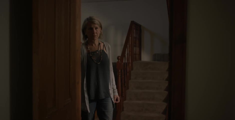 A woman is standing at a doorway and looking into a room