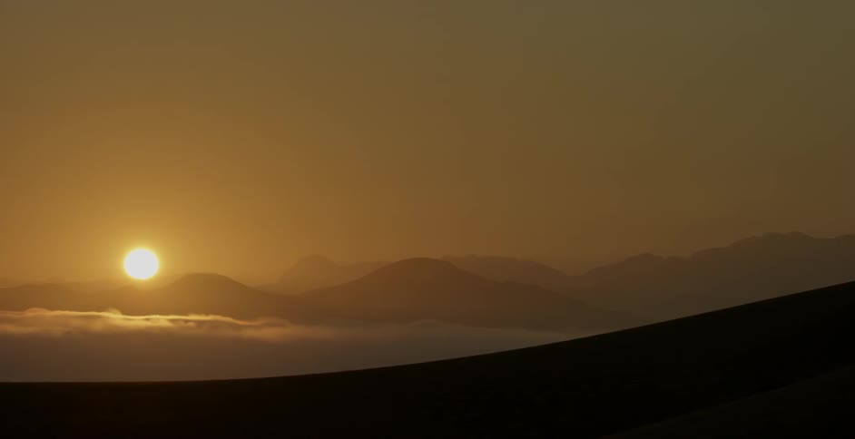 The sun is setting over the desert