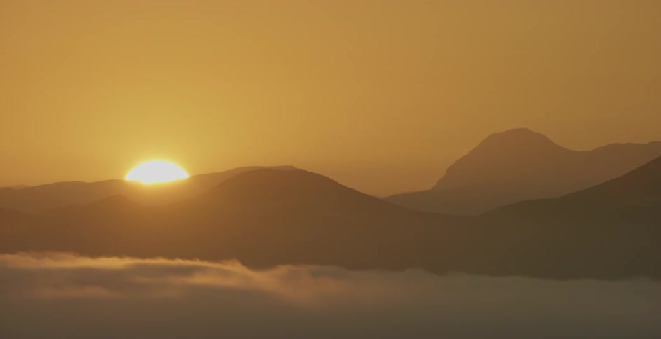 The sun is rising above the mountains