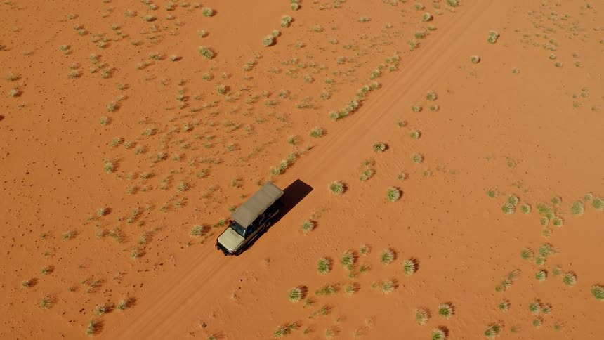 A car is being filmed from a drone driving through the desert